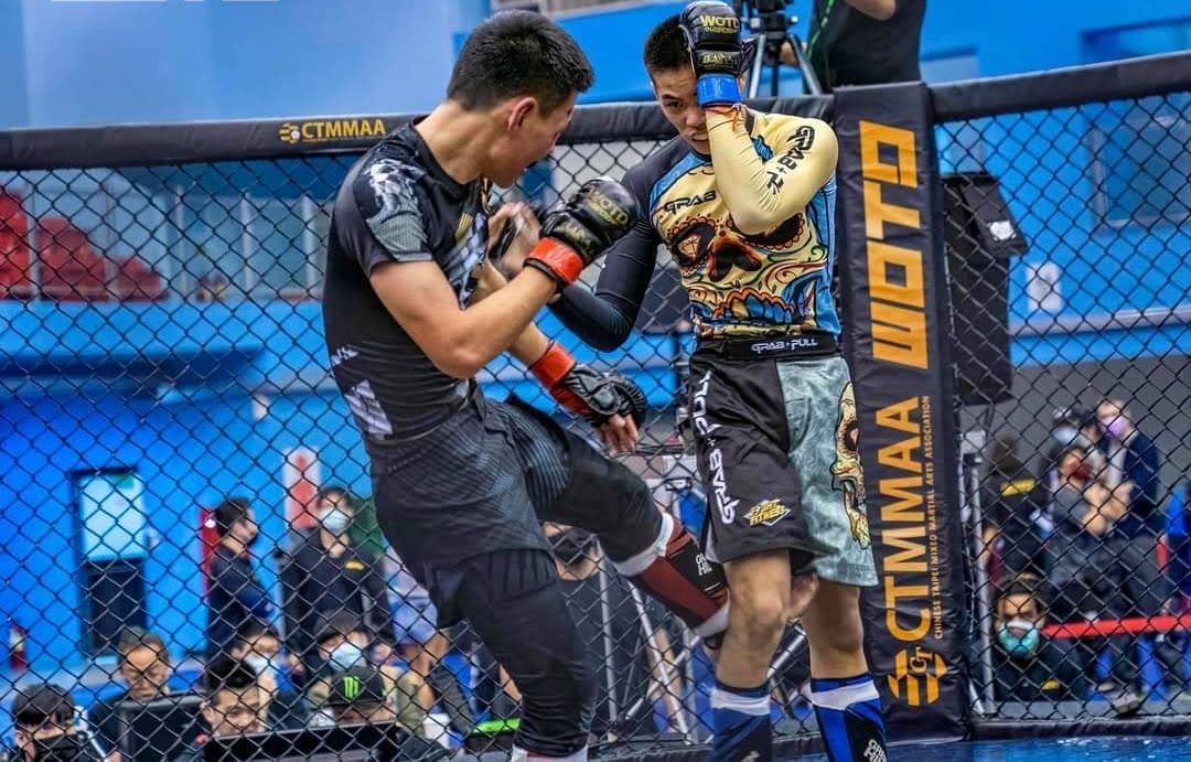 Two fighters exchange strikes against the cage